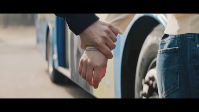 車輛旁的手牽手畫面 牽手的情侶站在電動巴士旁,展現愛情與科技.